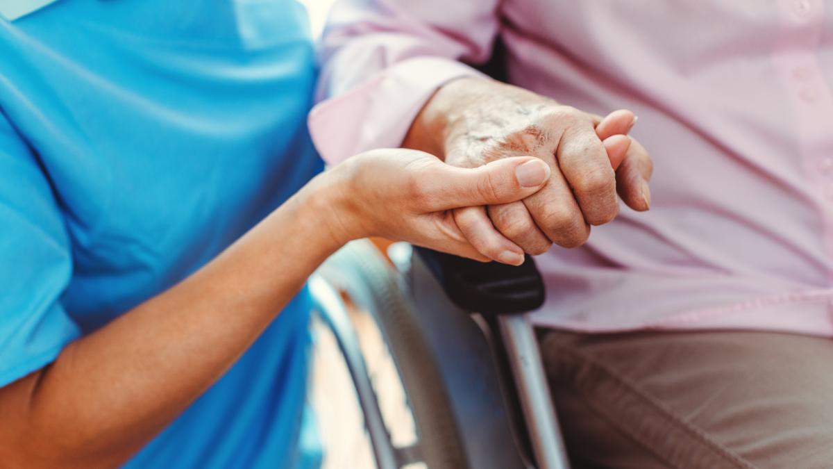 Nurse consoling a senior woman in the nursing home holding her hand